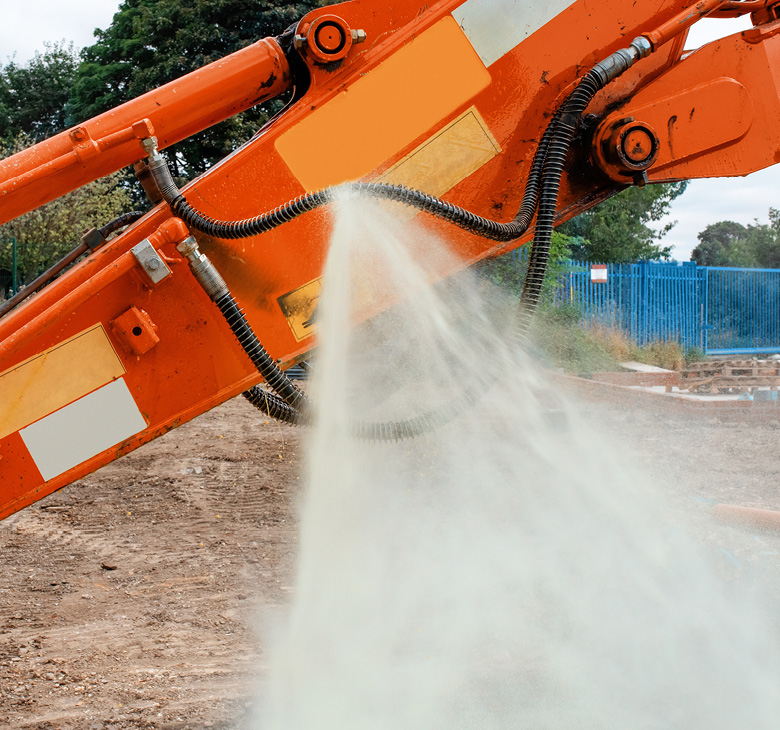 Orange construction machinery spraying hydraulic oil on site.