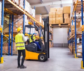Warehouse workers operating forklift with boxes